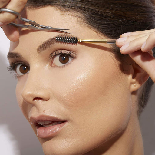 Female model using Tweezerman Eyebrow Shaping Scissors with brush
