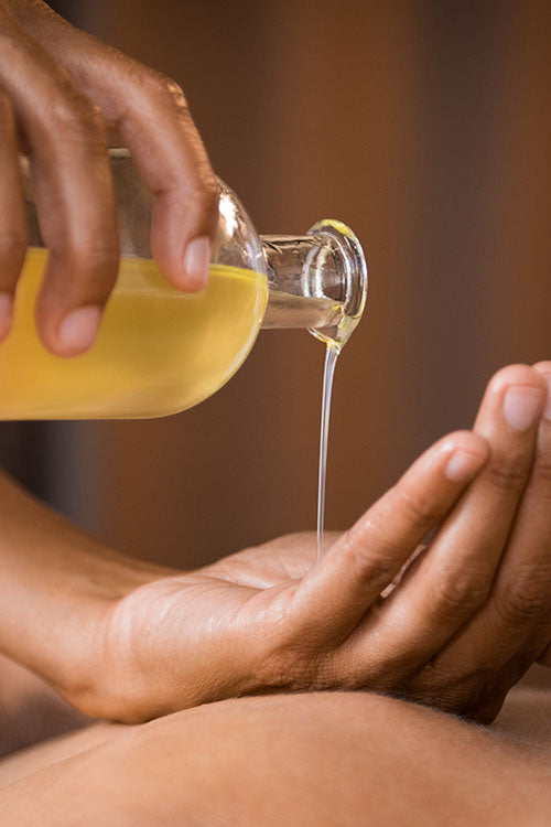 Massage oil being poured into the palm of a hand
