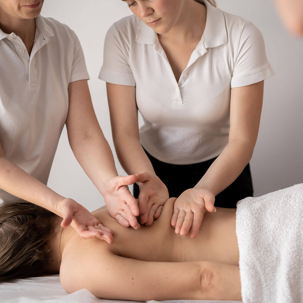 Massage therapy teacher with students working on a model