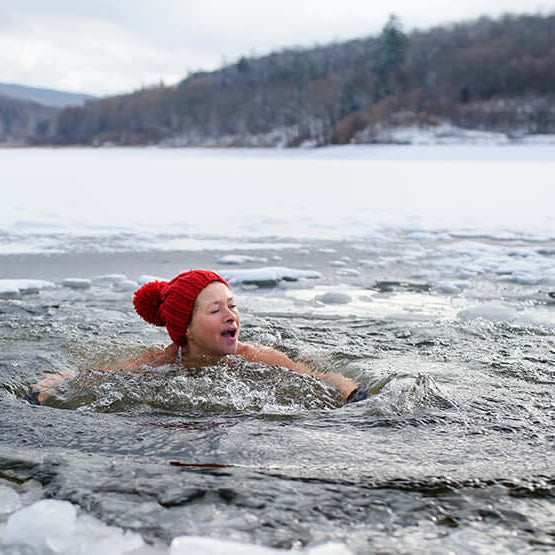 Woman swimming in ice cold water to show how does cold therapy work