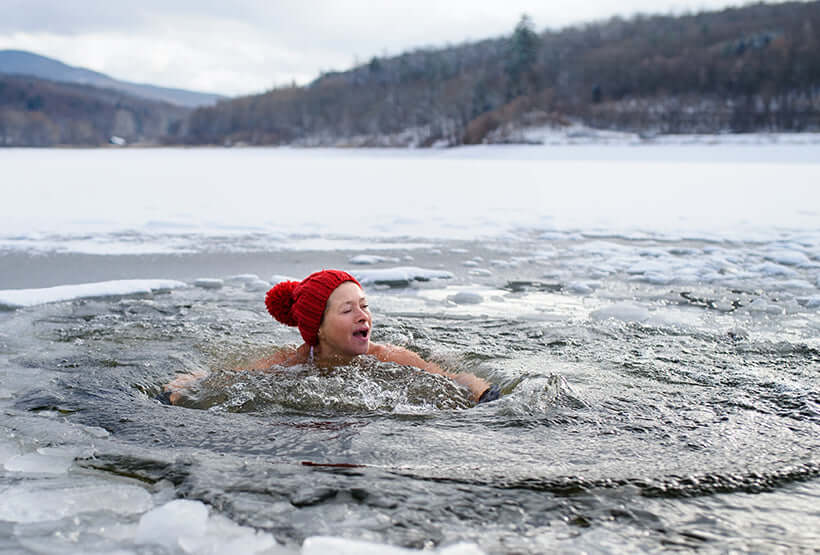 Woman swimming in ice cold water to show how does cold therapy work