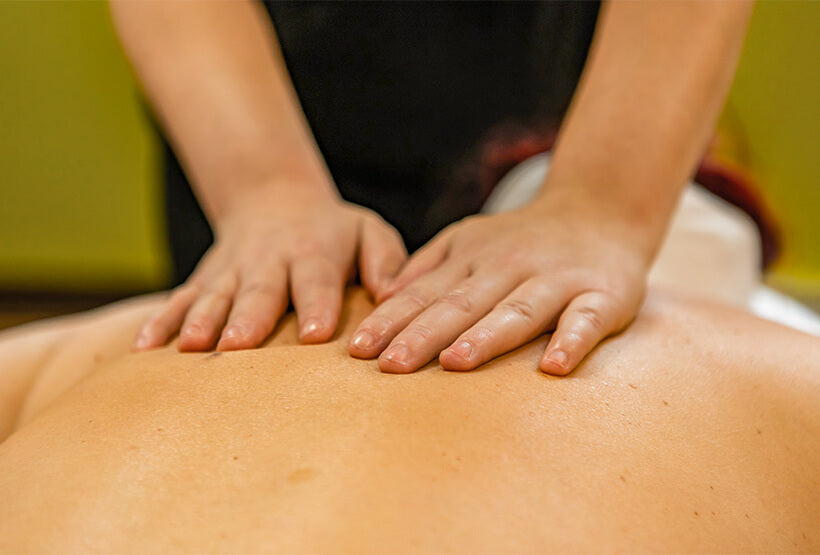 Massage therapist applying effleurage to patient's back