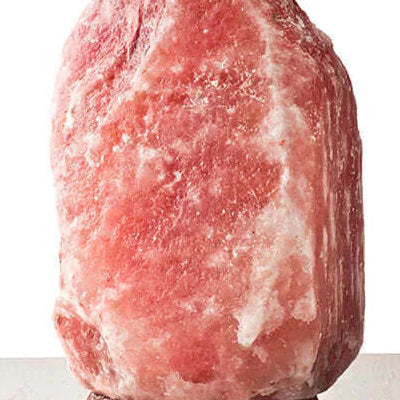Small Himalayan pink salt lamp on a wooden table for spa and wellness therapy
