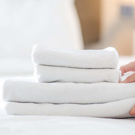 Hands place clean towels on the clean linens of a massage table