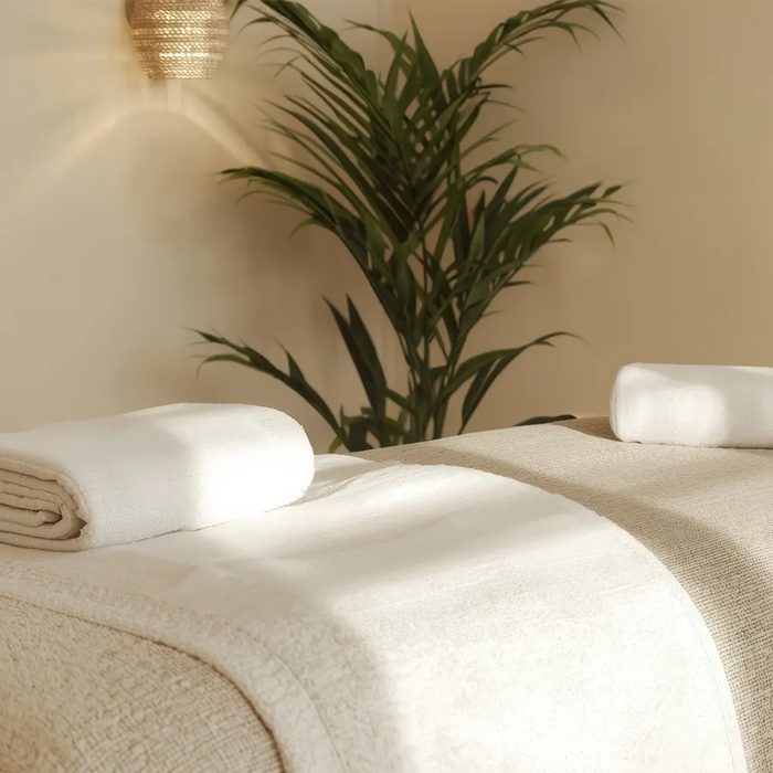 Professional massage treatment room with neatly prepared table, fresh white linens, folded towel and calming spa-inspired décor