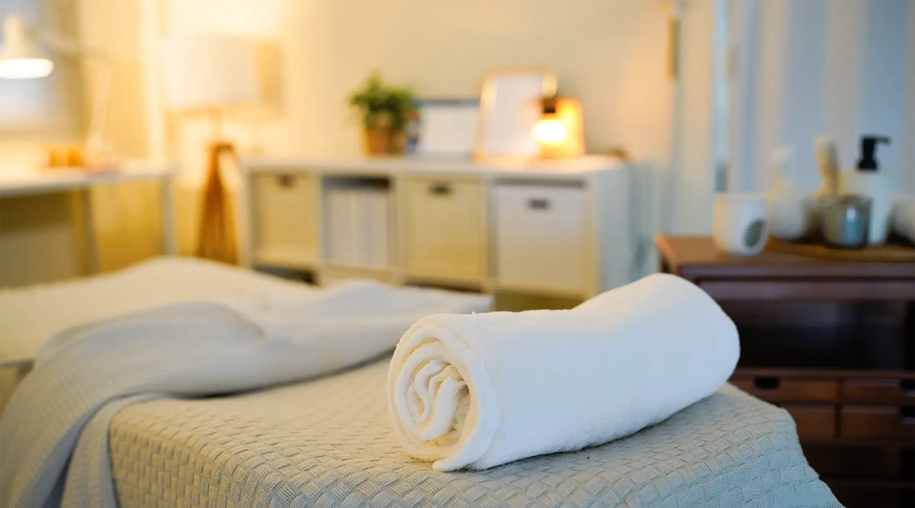Freshly prepared massage treatment room with clean linens and towels following client turnover and clinic hygiene procedures