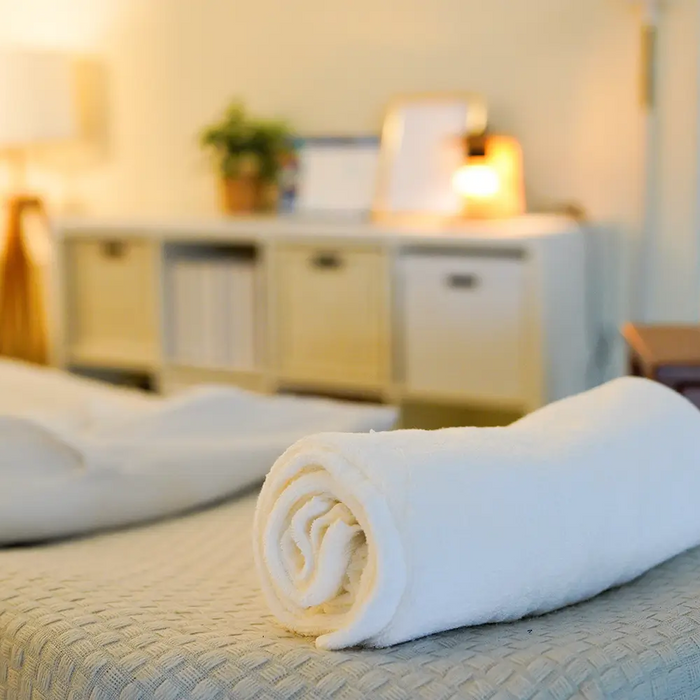 Freshly prepared massage treatment room with clean linens and towels following client turnover and clinic hygiene procedures