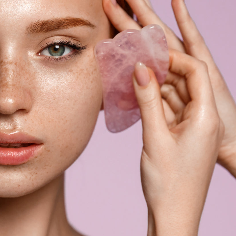 Woman using Gua sha massage tool on her face
