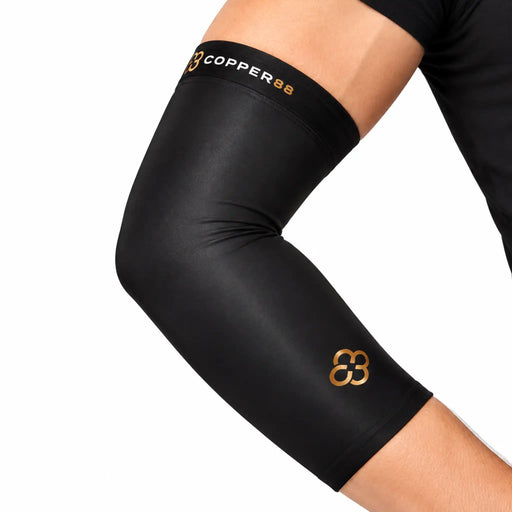 A close-up of a person's forearm wearing a black copper88 compression sleeve with gold branding.