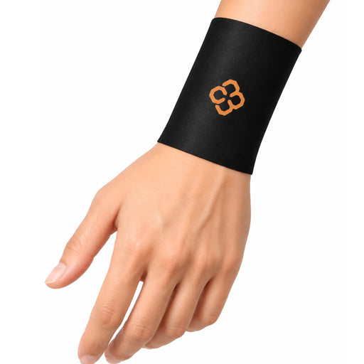 Copper88 black wrist support brace with an orange four-leaf clover logo, shown worn on a person's wrist against a plain white background.
