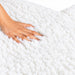 Close-up of Earthlite Professional Table Warmer's plush white fleece fabric with a hand pressing into the soft, cushioned surface.