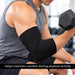 A close-up of a man in a gray tank top lifting a hex dumbbell, wearing a black MKO compression elbow support sleeve. A black banner at the bottom reads, 'Helps maintain comfort during physical activity'.