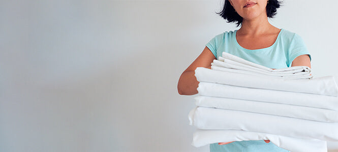 female holding a stack of folded sheets