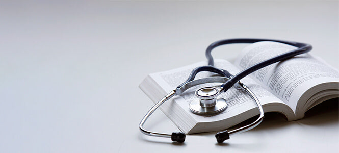 photo of an open book with a stethoscope lying on the pages