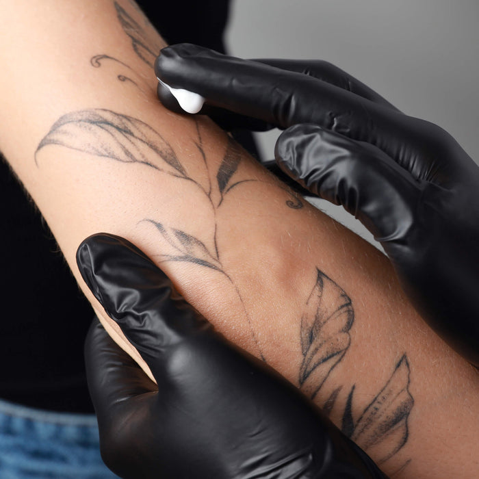 Zensa cream for tattoo's - tattooed arm being held by black gloved hand 