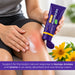 A person applies white cream to a red, bumped knee while holding a purple tube of Anti-Flamme Arnica  Pain Relief cream 90g. Yellow arnica flowers are visible in the foreground, and a purple text banner is at the bottom.
