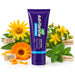 A purple squeeze tube of Anti-Flamme Soothing Herbal Pain Cream 100g centered on a white background, surrounded by yellow flowers, green leaves, and small paper labels reading Armica montana, Calendula officinalis, Hypericum, and Peppermint.
