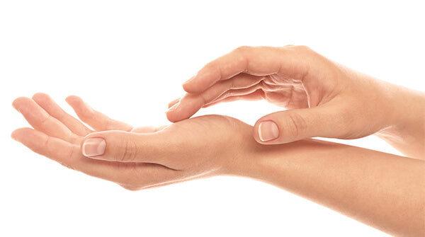 A banner photograph of a wrist and an open palm, receiving a light, precise touch from the fingertips of another hand.