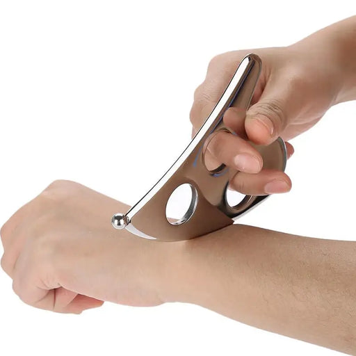 Hand using a quasha scraping tool on a white background