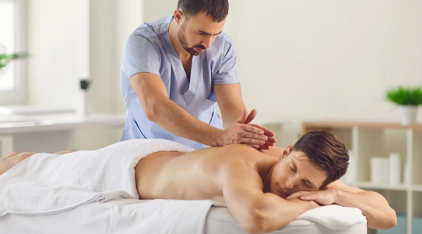 Bodybest man receiving a massage from a therapist in a clinical setting.