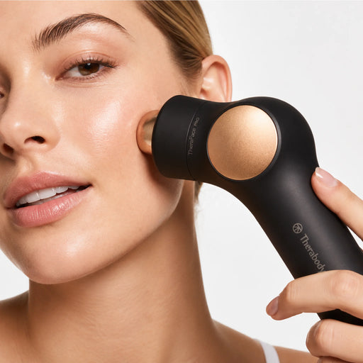 Therabody TheraFace PRO facial device used on cheek for facial massage and skincare treatment