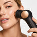 Therabody TheraFace PRO facial device used on cheek for facial massage and skincare treatment